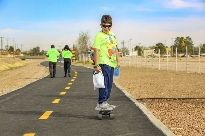 Young hispanic boy skateboarding on paved Paso Del Norte trail in El Paso