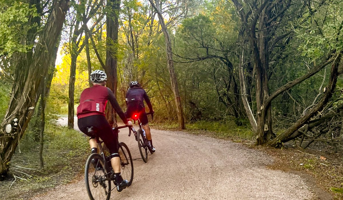 Two bikers on dirt trail surrounded by trees