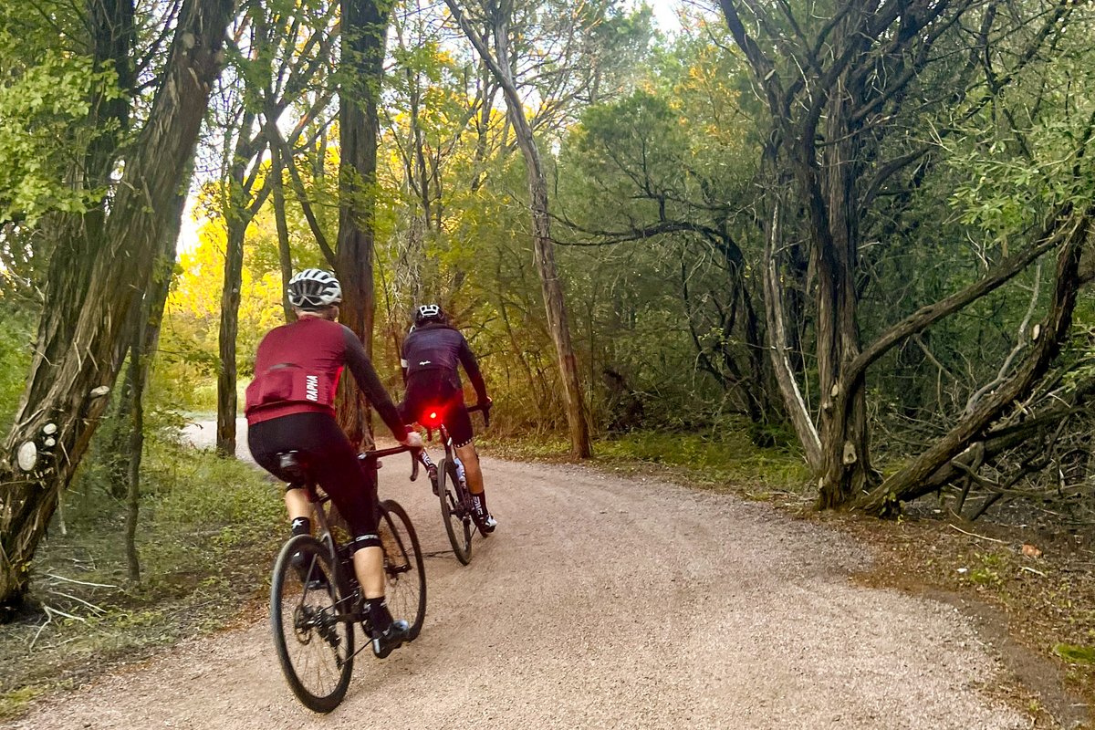 Two bikers on dirt trail surrounded by trees