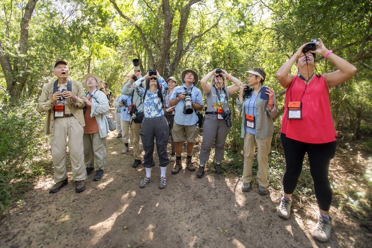 Group of people with binoculars and cameras on dirt trail