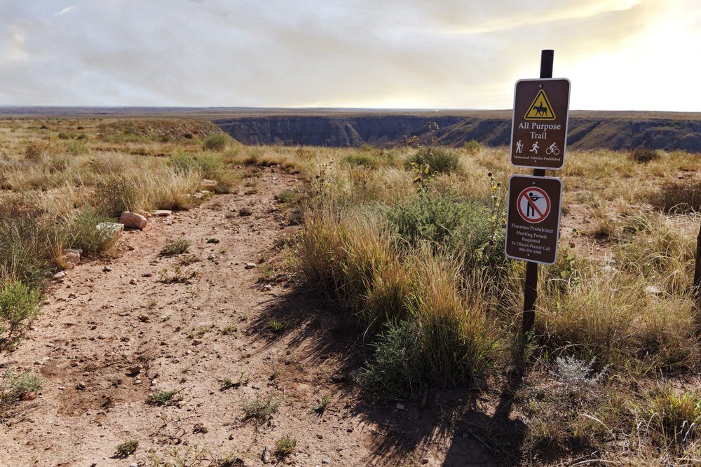 Red dirt trail with sign about trail rules in vast Texas Panhandle landscape