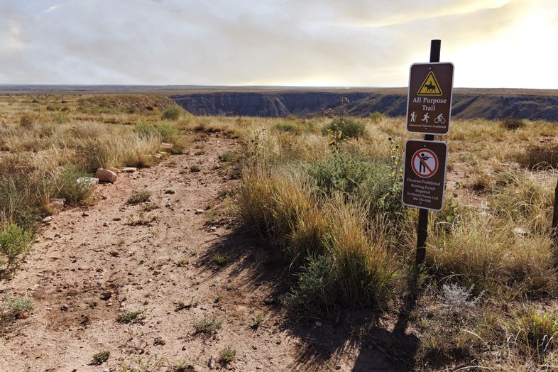 Red dirt trail with sign about trail rules in vast Texas Panhandle landscape