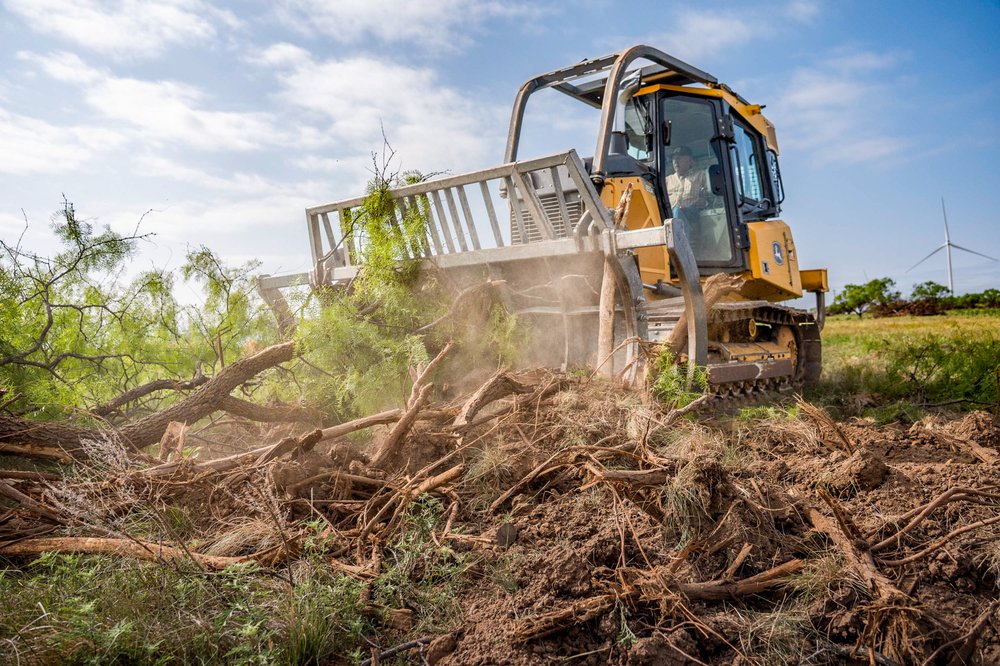 A bulldozer clearing trees in a prairie
