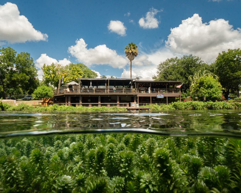 Clear water of the San Marcos River with a building in the background.