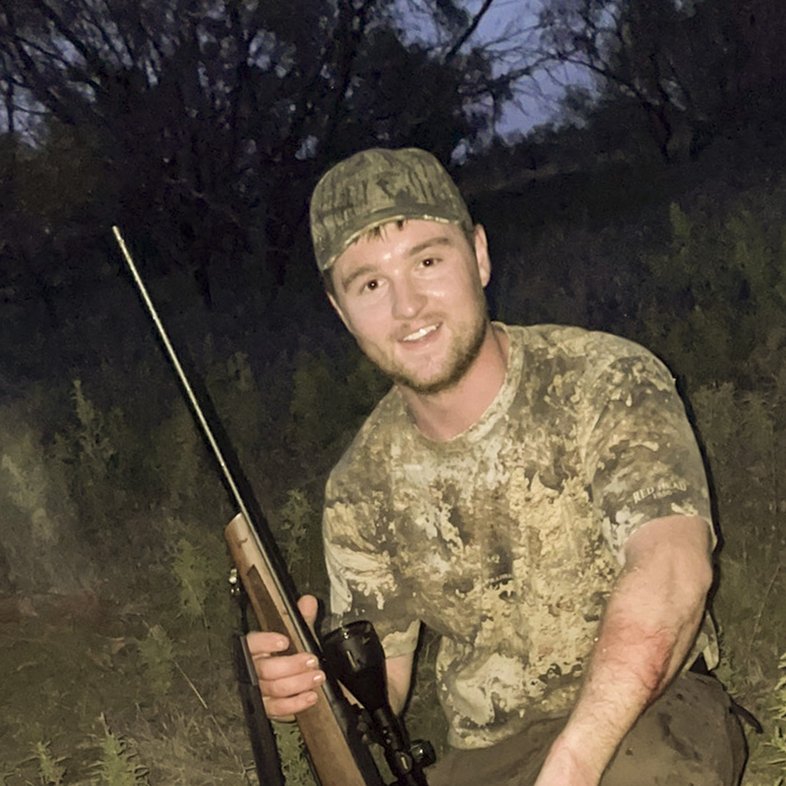 Dressed in camouflage, hunter Seth Driskell holds his deer hunting rifle