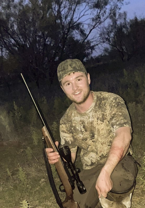Dressed in camouflage, hunter Seth Driskell holds his deer hunting rifle