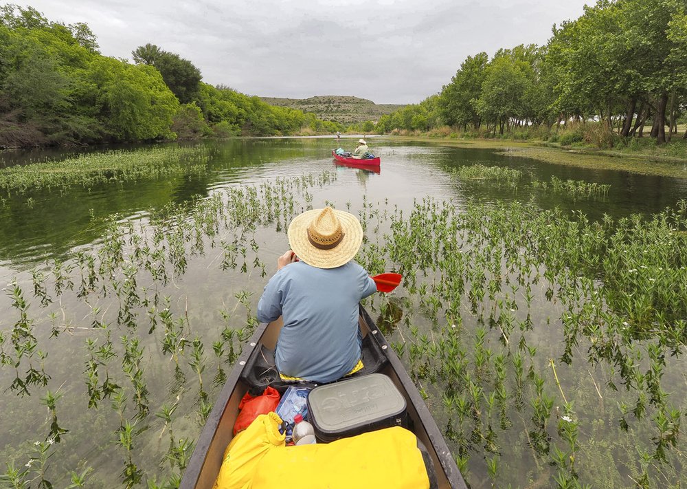 two paddlers in canoes navigate the river