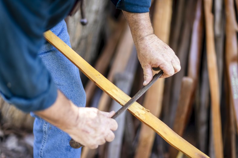 Person shaping wood for a traditional bow.