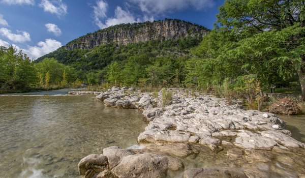 The Frio River at  Garner State Park with a cliff in the distance.