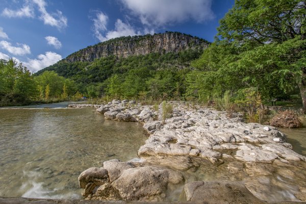 The Frio River at  Garner State Park with a cliff in the distance.