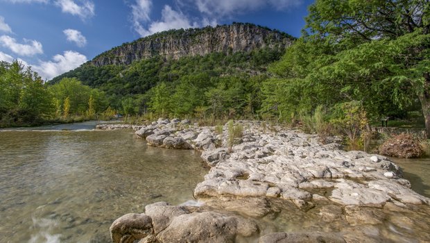 The Frio River at  Garner State Park with a cliff in the distance.