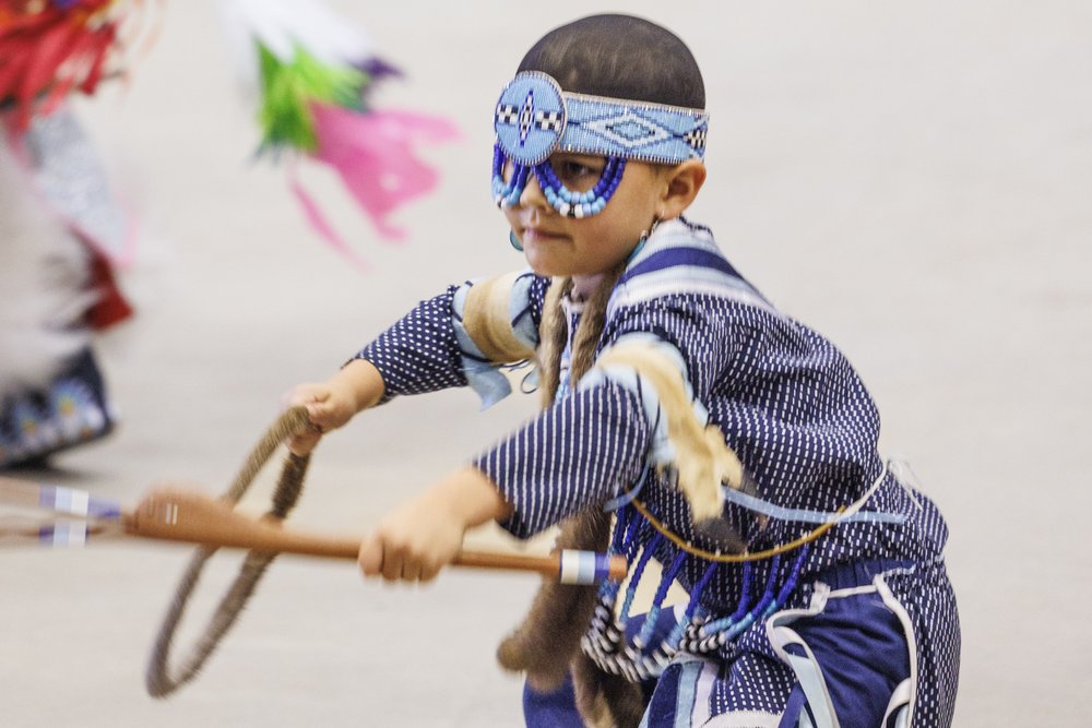 Child dressed in blue and wearing a mask at the annual Powwow at the Austin Convention Center.