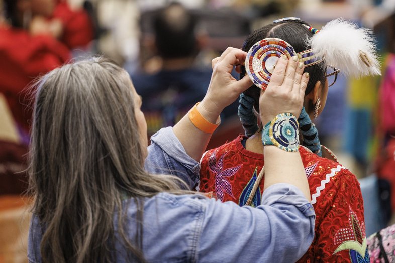 A person helping a dancer attach their headwear.