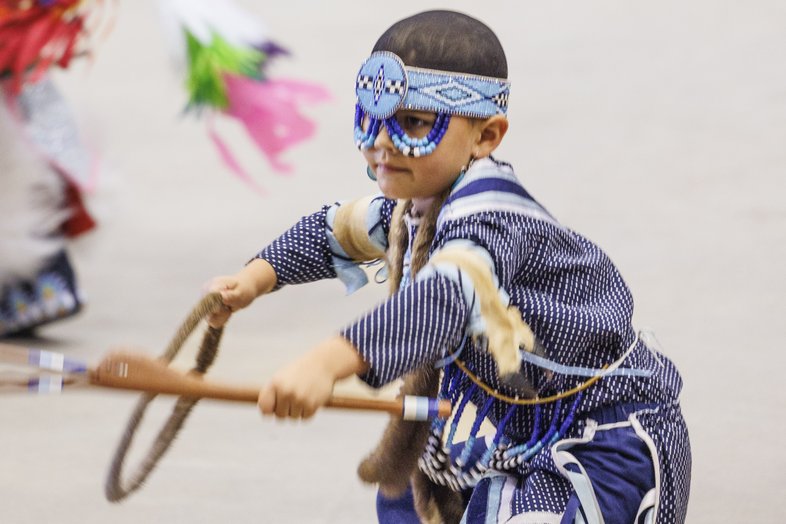 Child dressed in blue and wearing a mask at the annual Powwow at the Austin Convention Center.