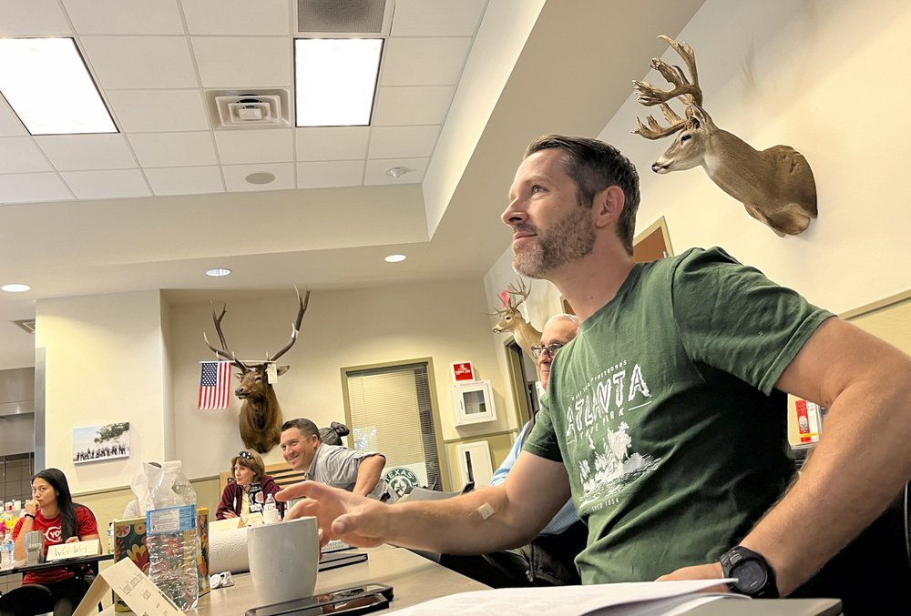 A man in a green shirt sits in a classroom