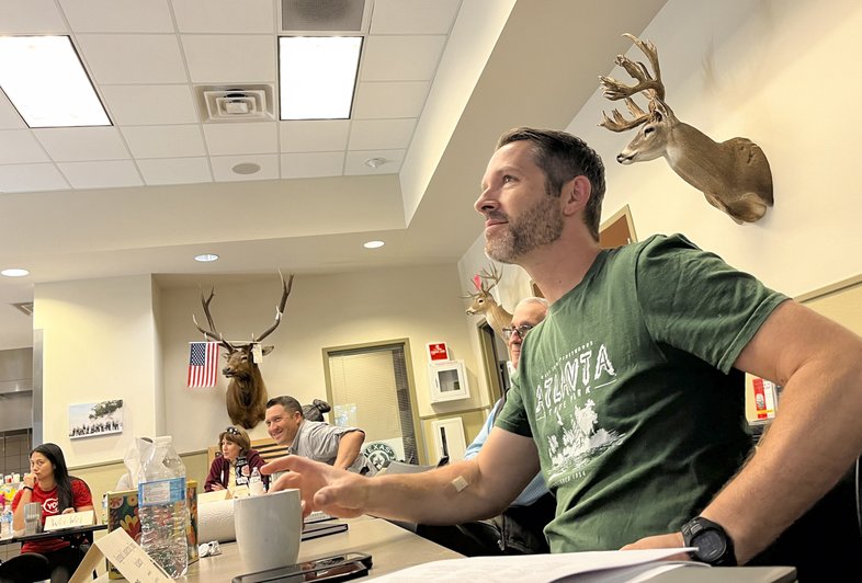 A man in a green shirt sits in a classroom