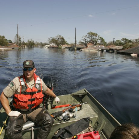 A game warden driving a boat through flooded waters