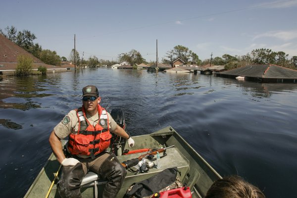 A game warden driving a boat through flooded waters