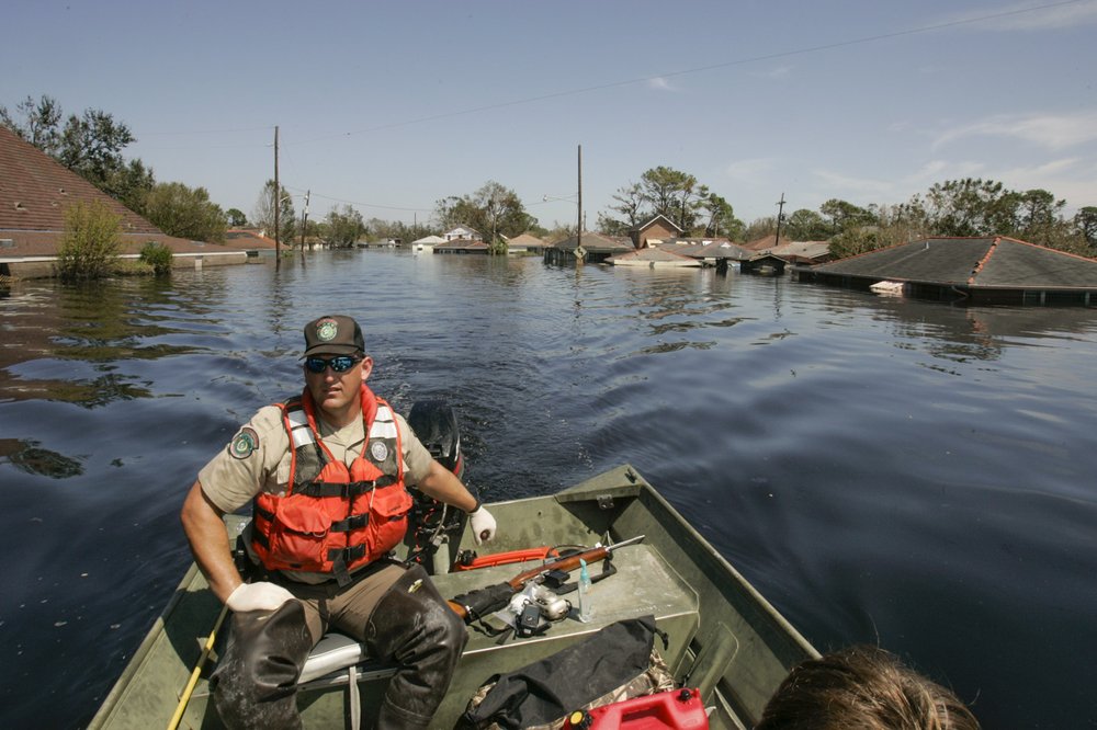 A game warden driving a boat through flooded waters