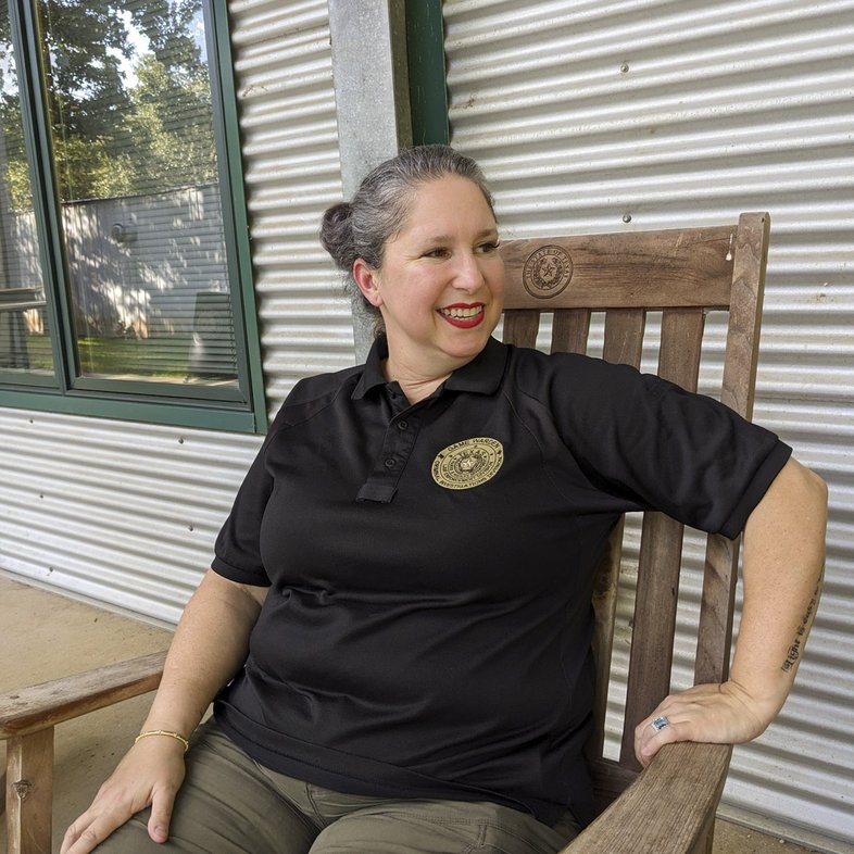 Game Warden Cynthia Guajardo-Echols sits in a wooden chair on a front porch