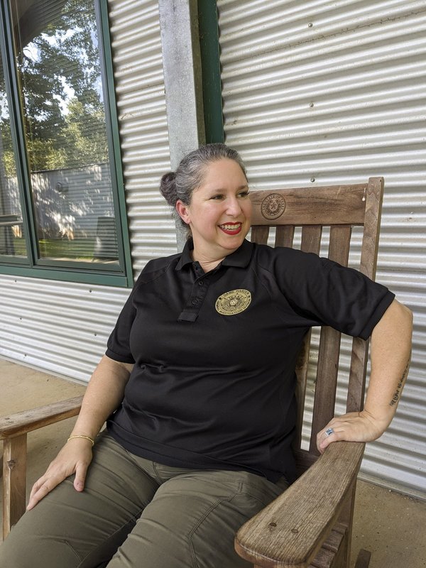 Game Warden Cynthia Guajardo-Echols sits in a wooden chair on a front porch