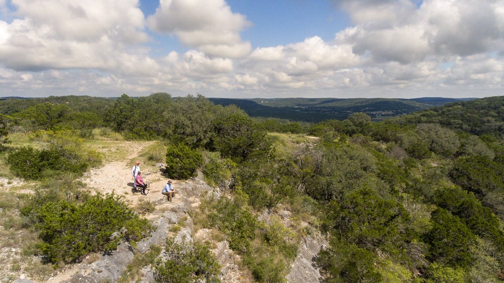 A group of people rest on a bench at a scenic overlook.