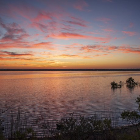 A sunrise with pink clouds over the lake.