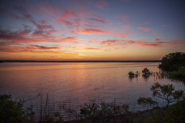 A sunrise with pink clouds over the lake.