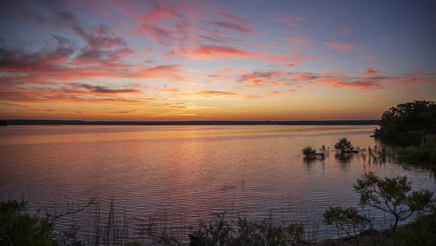 A sunrise with pink clouds over the lake.