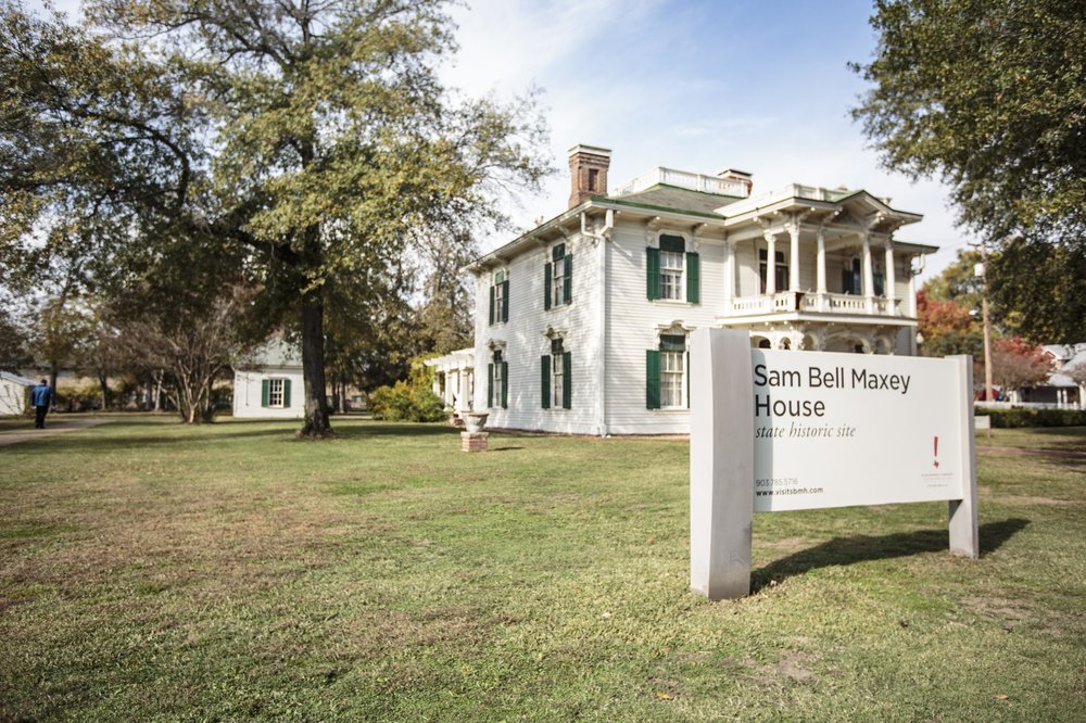 A white historic house with a sign in front that says "Sam Bell Maxey House"