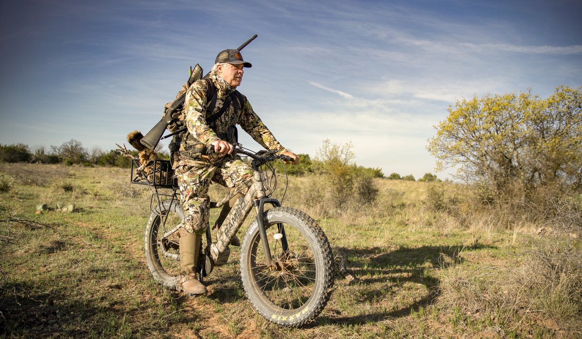 Man riding an e-bike with a gun while hunting.