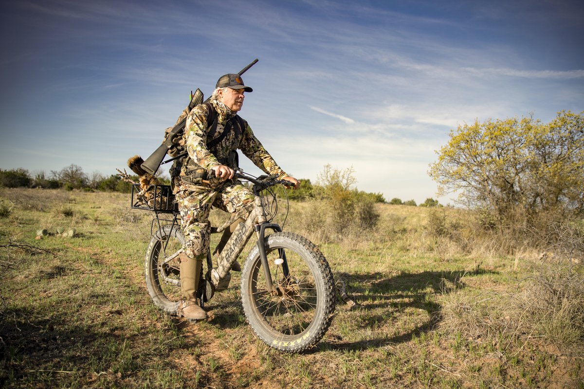 Man riding an e-bike with a gun while hunting.