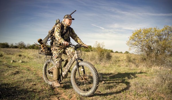 Man riding an e-bike with a gun while hunting.