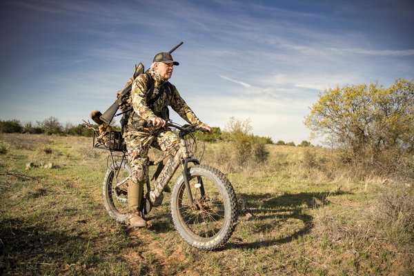 Man riding an e-bike with a gun while hunting.