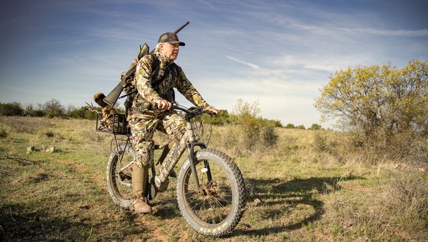 Man riding an e-bike with a gun while hunting.