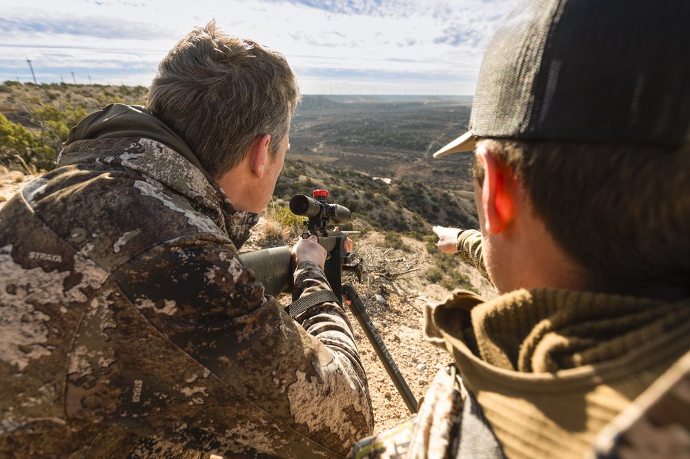 Two people hunt at the edge of a canyon.