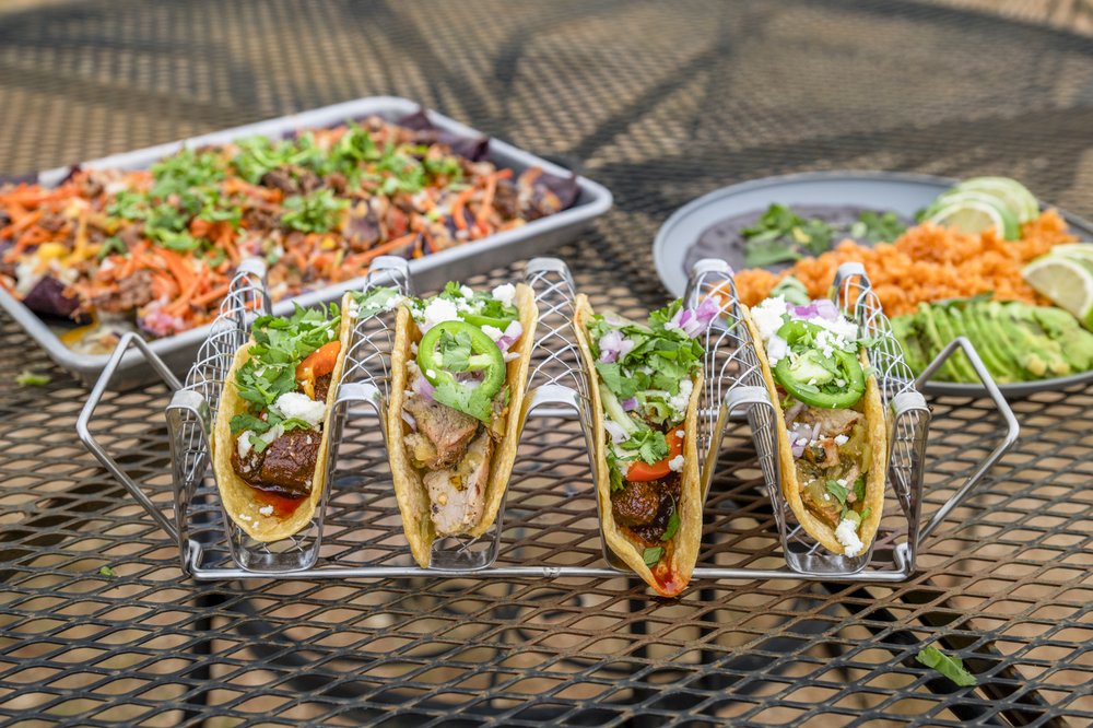 A table with tacos, nachos and sides made from invasive species.