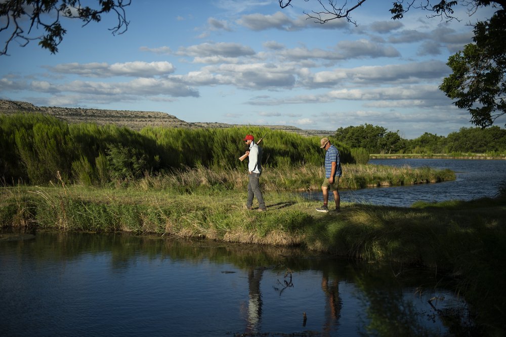 Men walking by water hunting nutria.