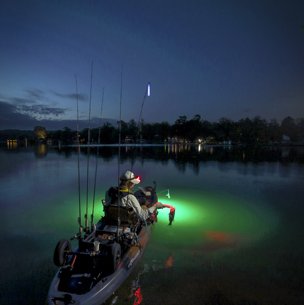Person in a boat Bass fishing from a kayak on Lake Austin with an underwater green light.