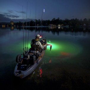 Person in a boat Bass fishing from a kayak on Lake Austin with an underwater green light.