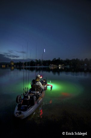 Person in a boat Bass fishing from a kayak on Lake Austin with an underwater green light.