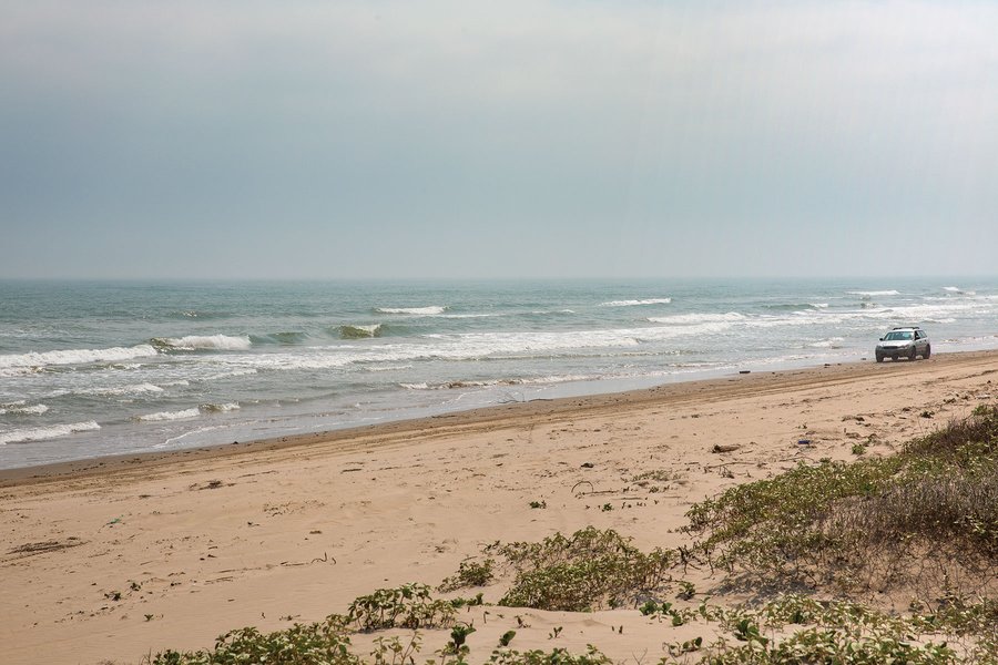 A car diriving down the beach.