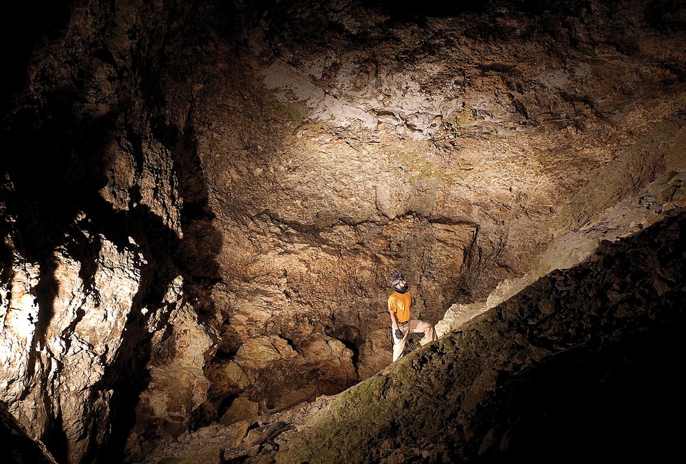 A cave explorer walking up an incline in a cave.