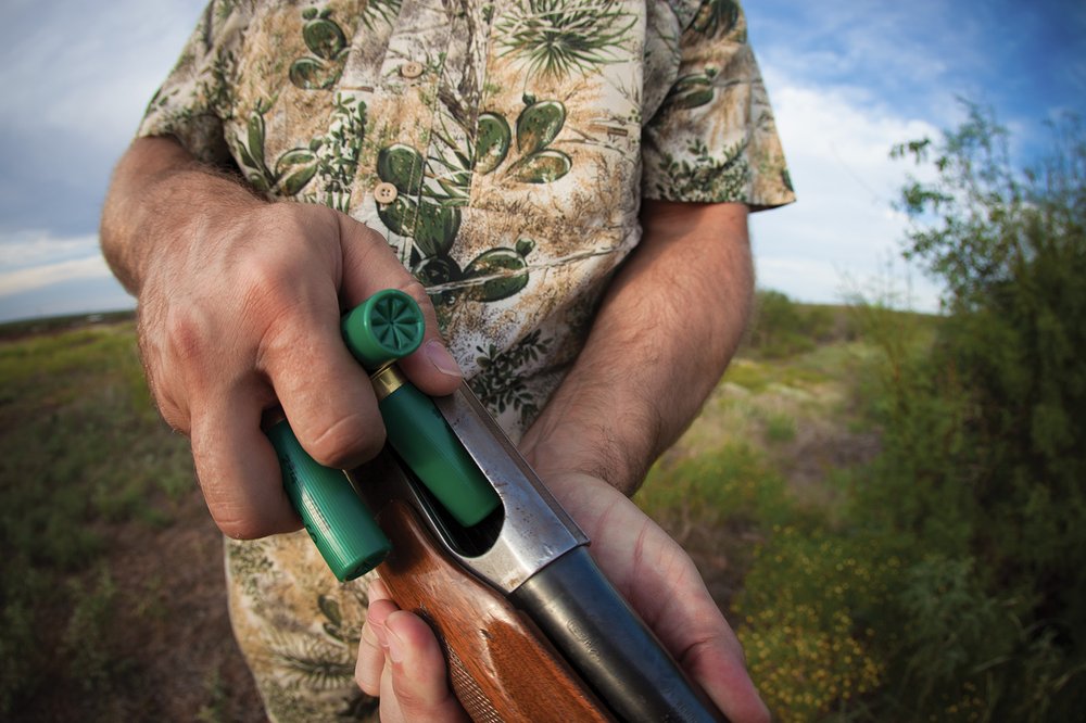 A close up of a person loading rounds into a gun.