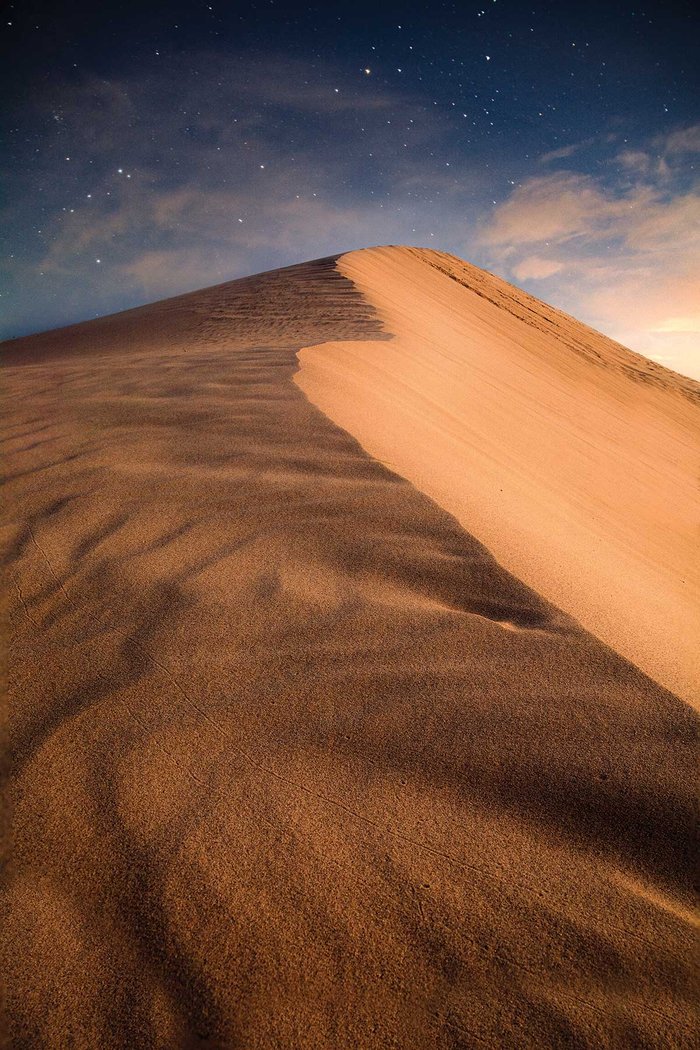A sand dune against a starry sky.