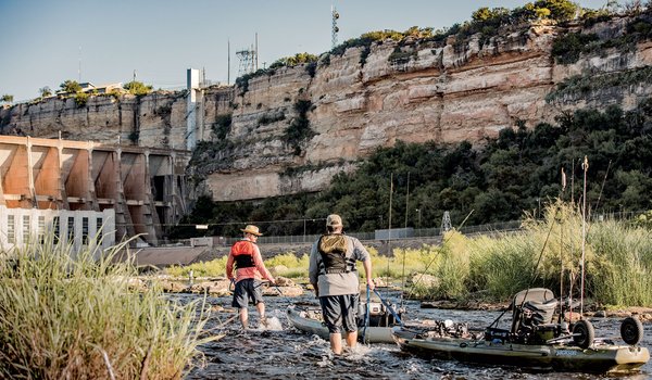 Anglers in the water near a dam.