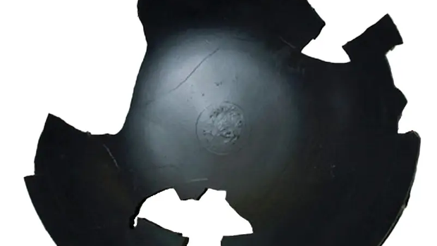 Black pieced together wok artifact with some pieces missing