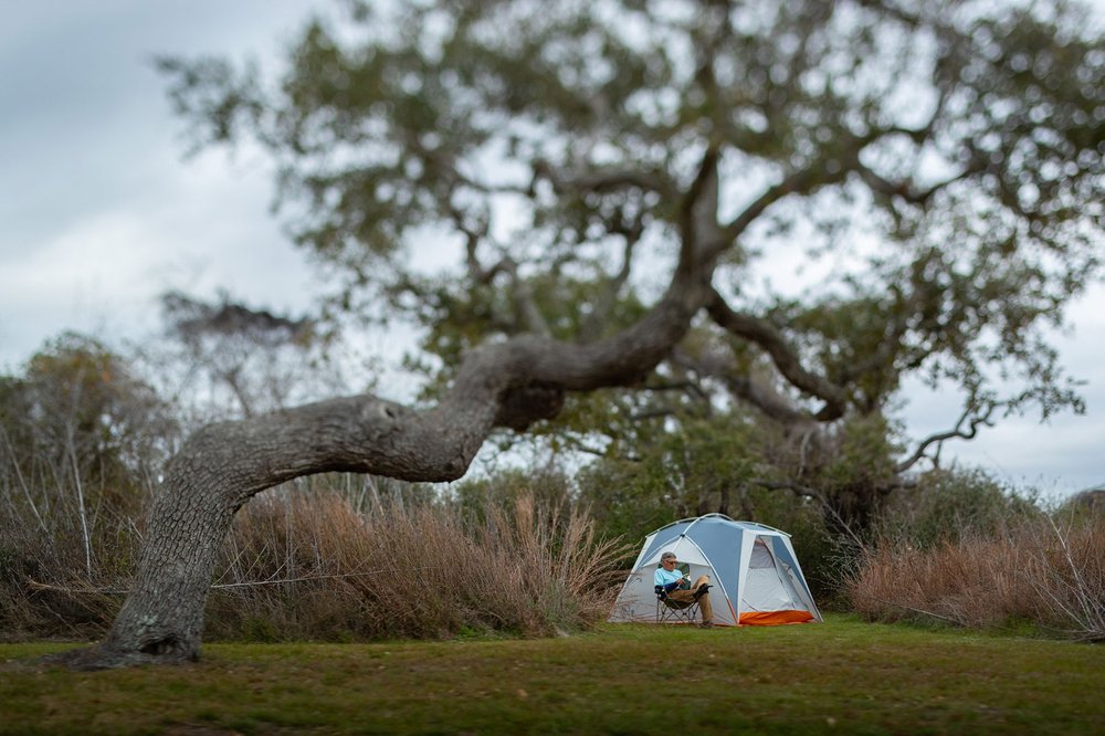 Man sitting near a tent camping at Goose Island
