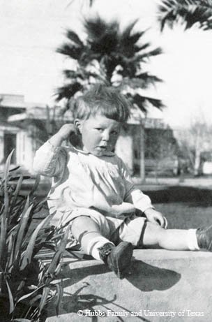 Black and White Photo of Clark Hubbs as a toddler sitting on a sidewalk
