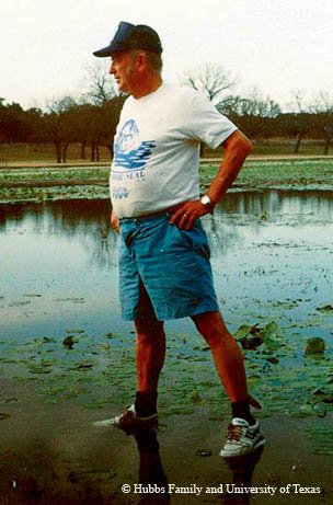 Clark Hubbs in baseball cap standing at the edge of water